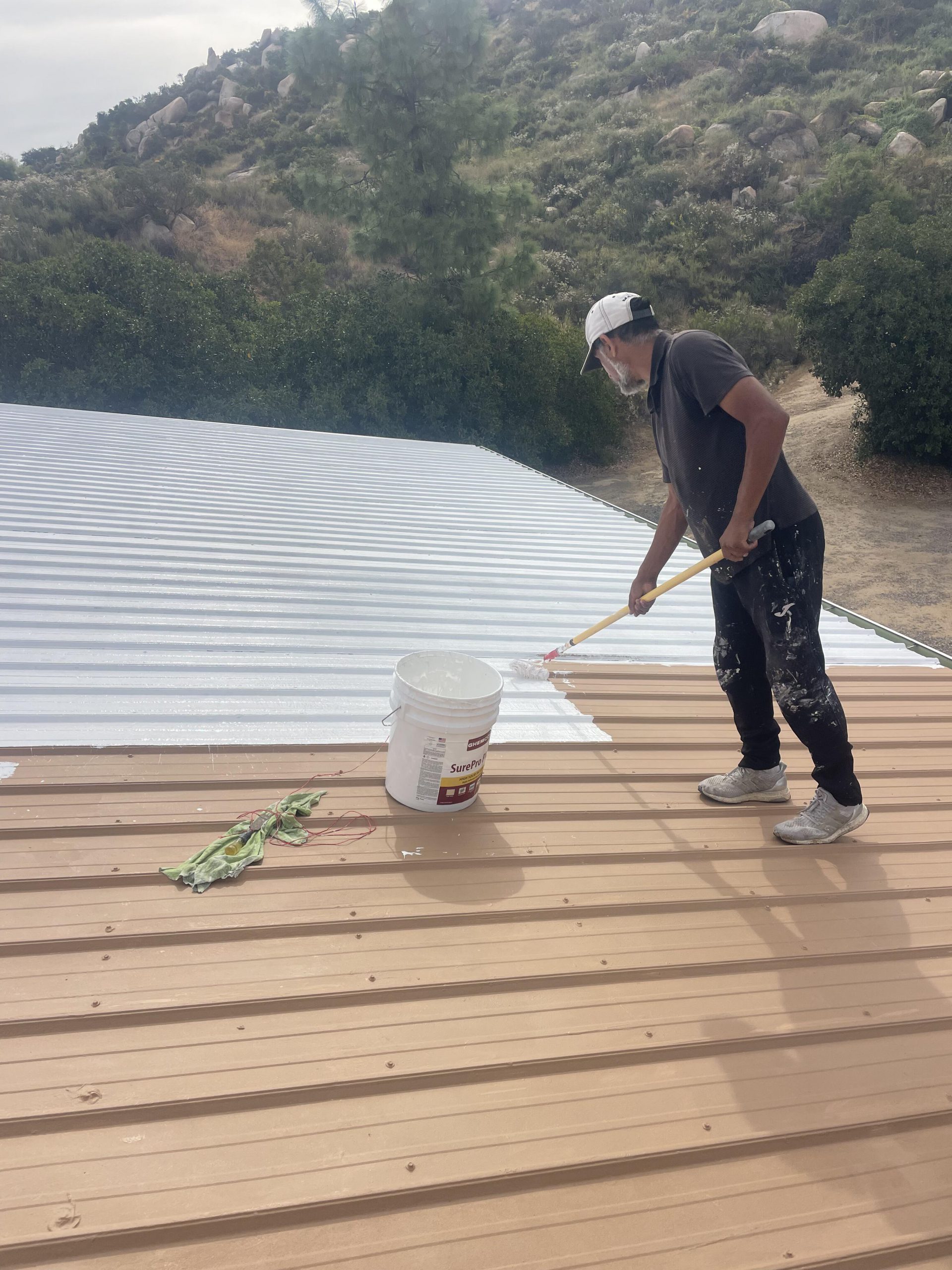 Applying reflective roof coating to a metal roof in San Diego County by Luna Roofing